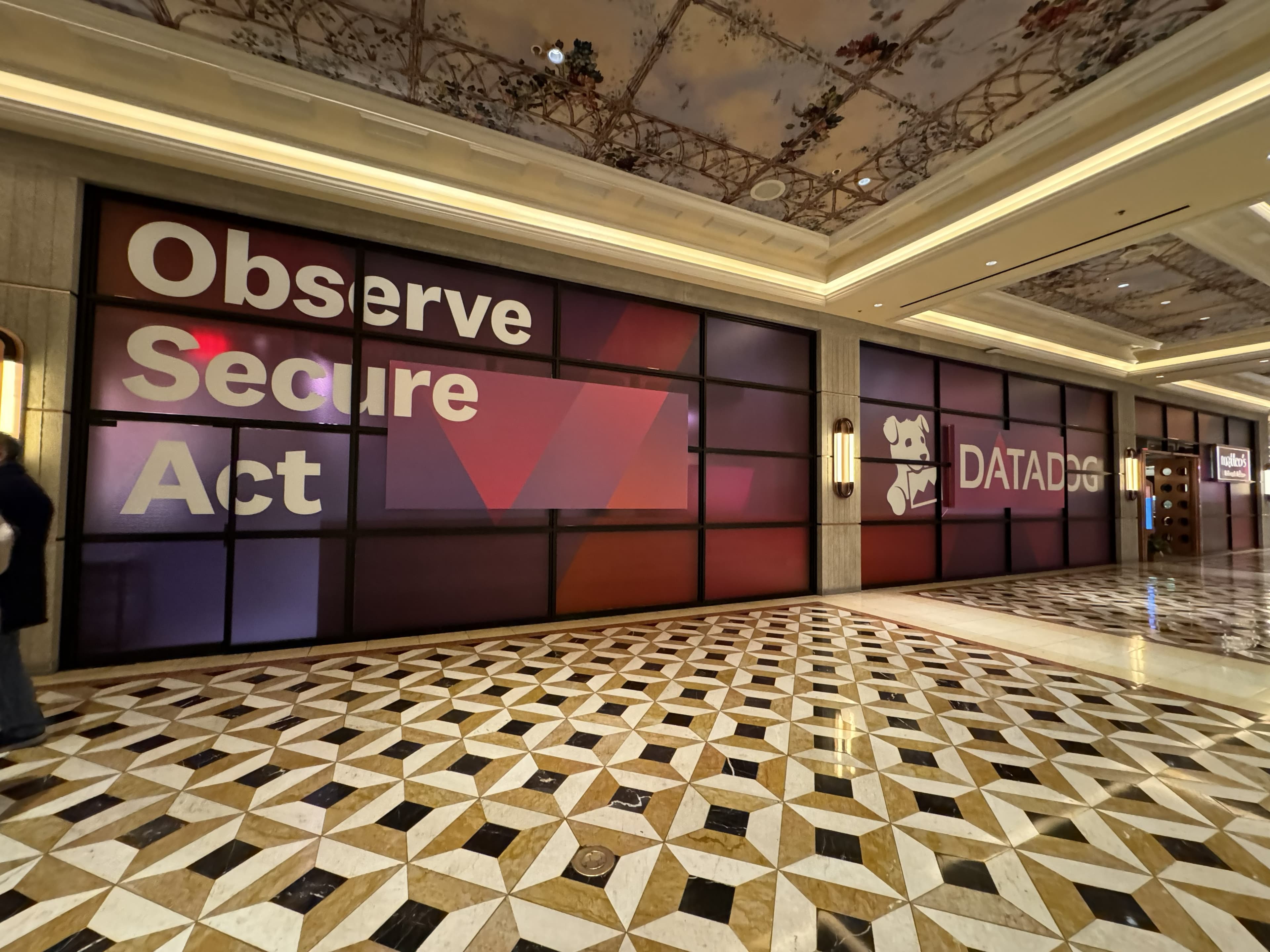 Datadog promotional graphics installed across a row of glass panels